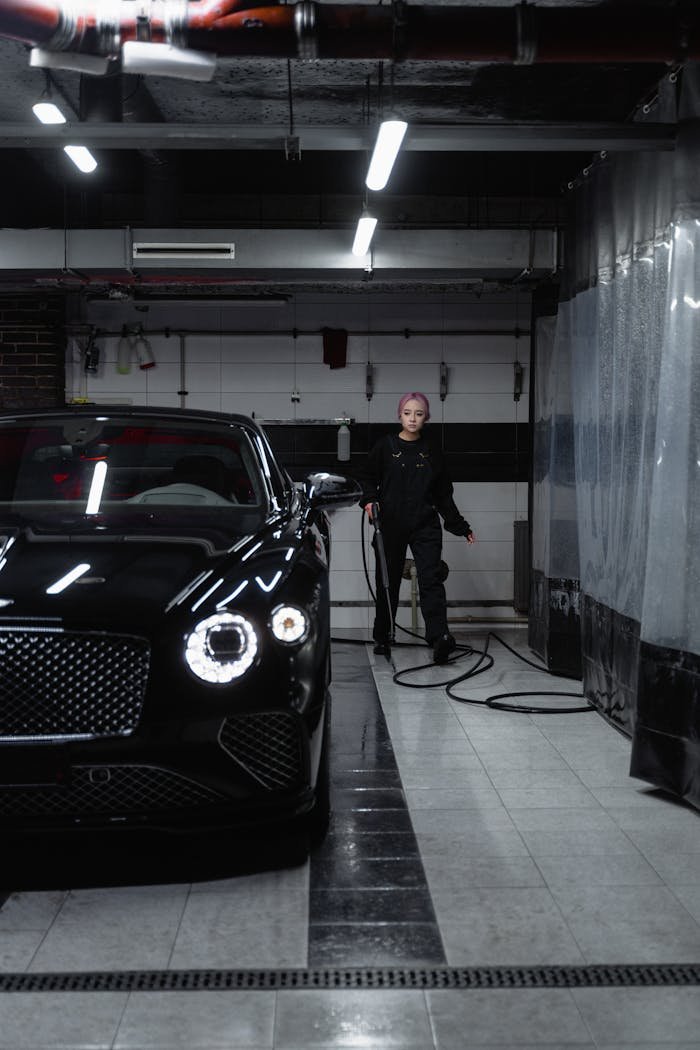 A stylish black car receiving a wash in a sleek, modern indoor facility.